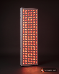 Revival Panel Corona red light therapy panel, front-facing angle, powered on with warm ember glow