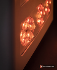 Revival Panel Corona red light therapy panel, LED close-up detail, powered on with warm ember glow