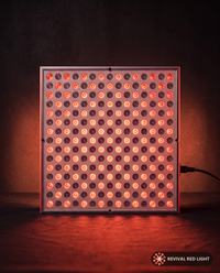 Revival Panel Glow red light therapy panel, front-facing angle, powered on with warm ember glow